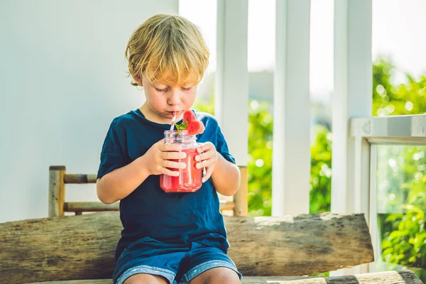 その少年が健康的なスイカのスムージーを保持しています。 — ストック写真