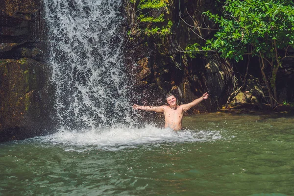 Uomo con le braccia in piedi contro la cascata . — Foto Stock