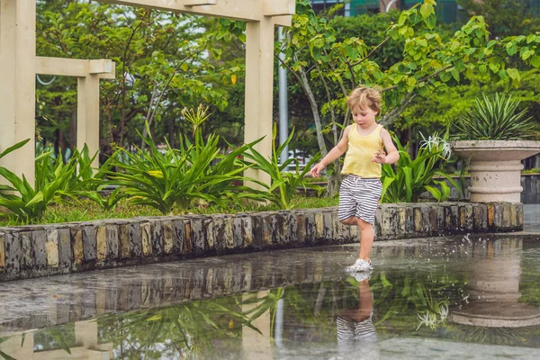 Pequeño niño corre a través de un charco — Foto de Stock