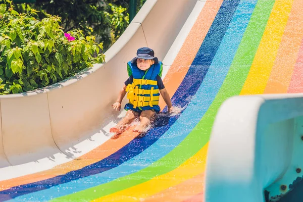 Menino desliza para baixo de um slide — Fotografia de Stock