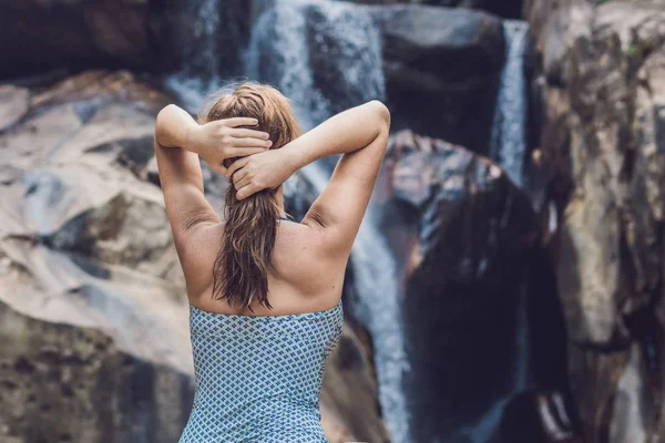 Женщина стоит на фоне водопада — стоковое фото