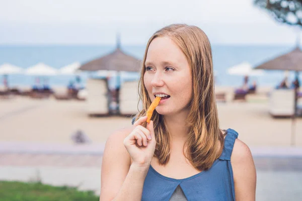 Женщина ест жареную сладкую картошку — стоковое фото