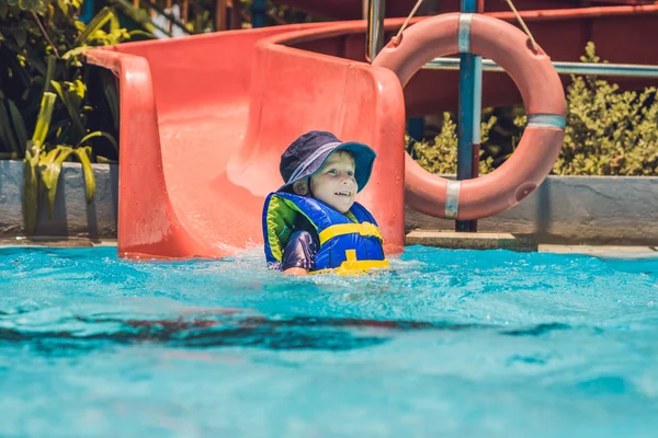 Menino desliza para baixo de um slide — Fotografia de Stock