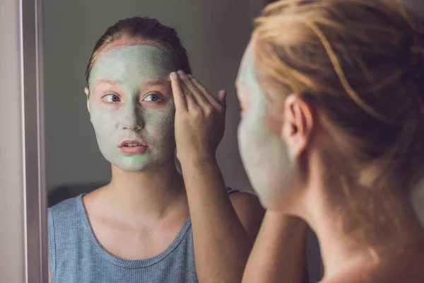 Женщина надевает маску из зеленой глины для лица — стоковое фото