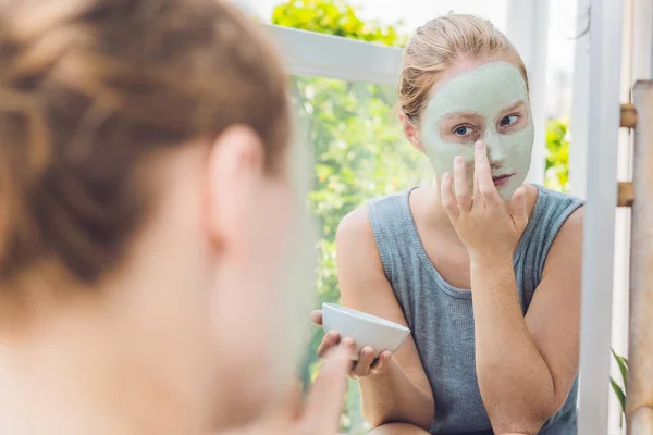 Mujer aplicando Facial máscara de arcilla verde — Foto de Stock