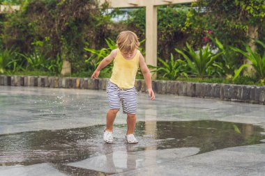 Küçük çocuk bir su birikintisi ile çalışır