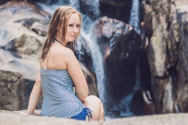  kadın bir şelale arka plan üzerinde oturur.