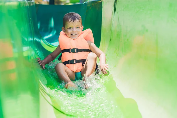 Menino desliza para baixo de um slide — Fotografia de Stock