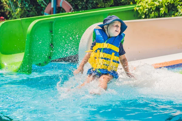 Menino em um colete salva-vidas desliza para baixo — Fotografia de Stock