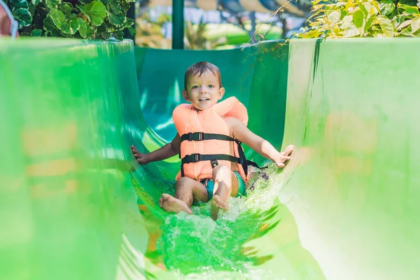Niño en un chaleco salvavidas se desliza hacia abajo — Foto de Stock