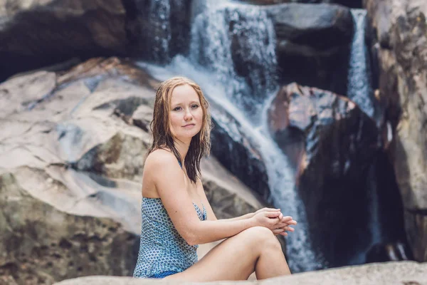 Vrouw zit op de achtergrond van een waterval. — Stockfoto