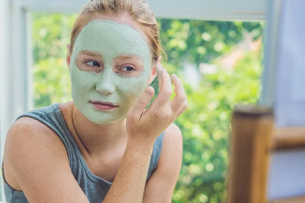 Hermosa chica aplicando máscara facial . — Foto de Stock