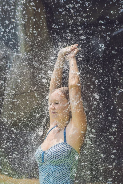 Jonge vrouw ontspannen onder een waterval — Stockfoto