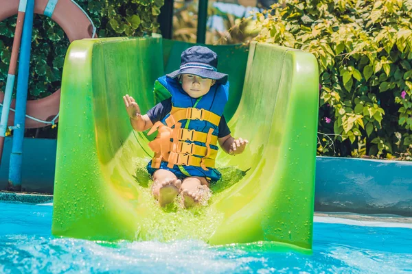 Jongen in een zwemvest glijdt naar beneden — Stockfoto