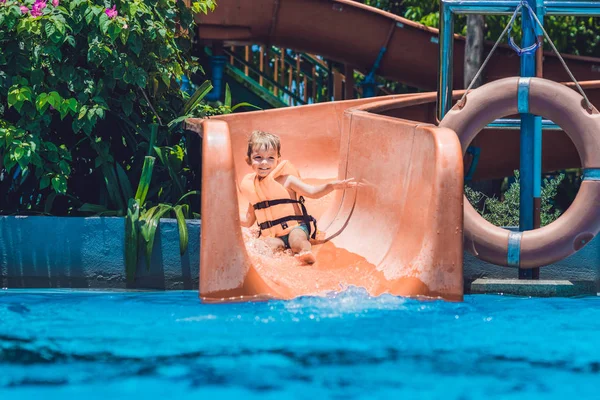 Jongen in een zwemvest glijdt naar beneden — Stockfoto