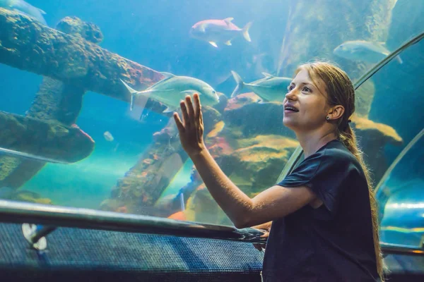 Jonge vrouw vissen in een aquarium van de tunnel kijken — Stockfoto