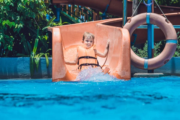 Niño en un chaleco salvavidas se desliza hacia abajo — Foto de Stock