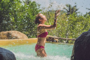 Genç kadın bir şelale altında rahatlatıcı