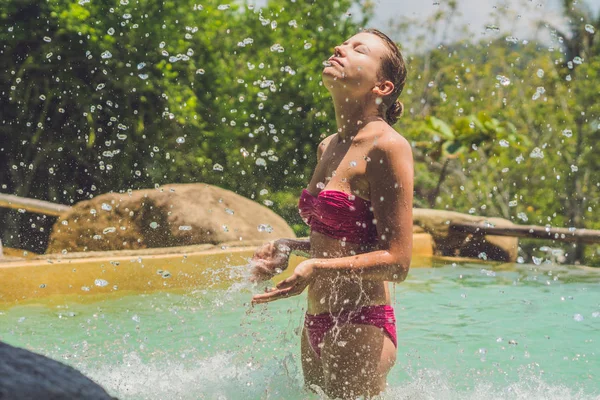 Junge Frau entspannt sich unter einem Wasserfall — Stockfoto