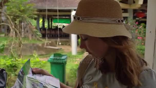 Young woman in a hat reading a map — Stock Video