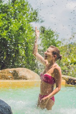 Genç kadın bir şelale altında rahatlatıcı