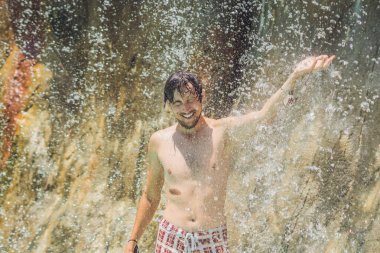 Genç adam bir şelale altında rahatlatıcı 