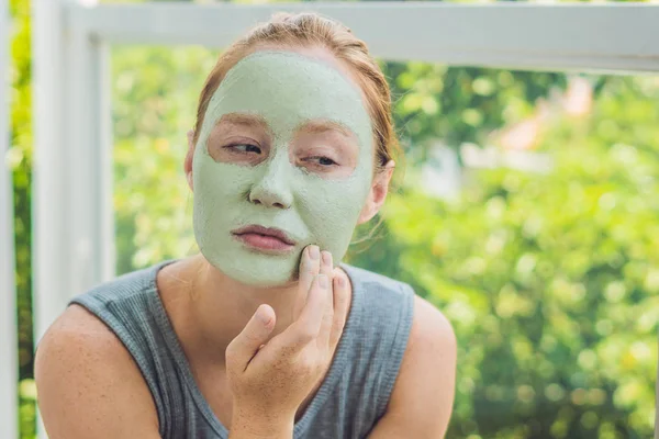Женщина надевает маску из зеленой глины для лица — стоковое фото