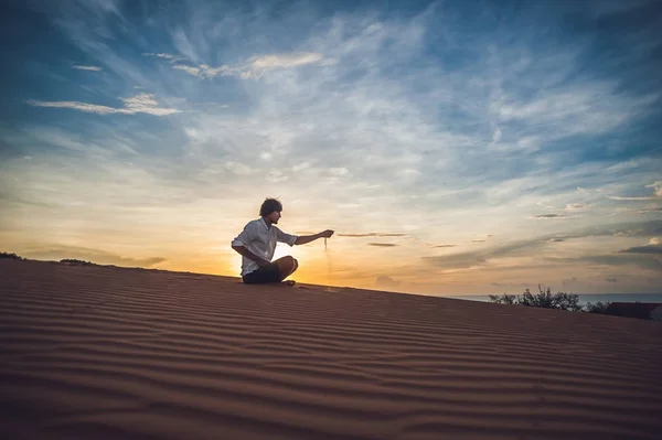 Man is het gieten van zand in de woestijn. — Stockfoto