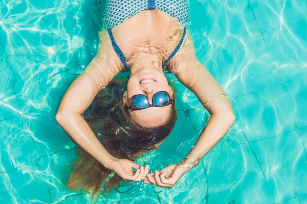 Beautiful young woman floating in pool