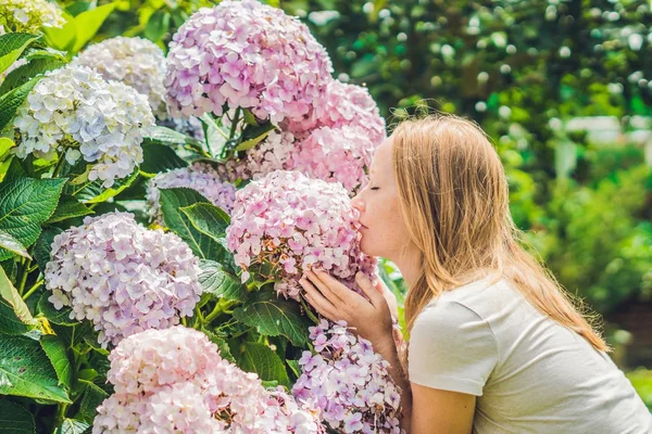 Jovem mulher perto de flores de hortênsia rosa — Fotografia de Stock