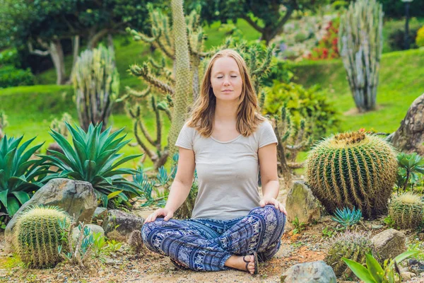 Young woman is meditating among a cactus — Stock Photo, Image
