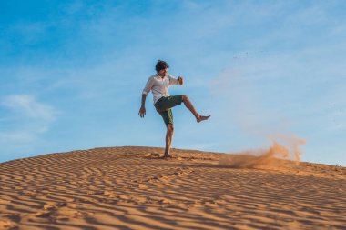  adam kırmızı bir çölde kum tekme atıyor
