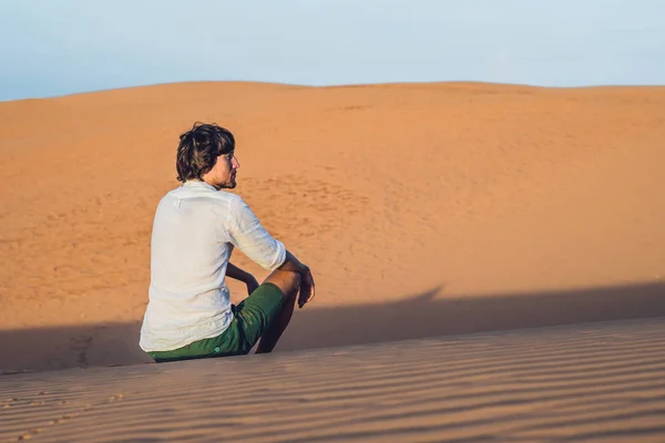 En man sitter på sanden — Stockfoto