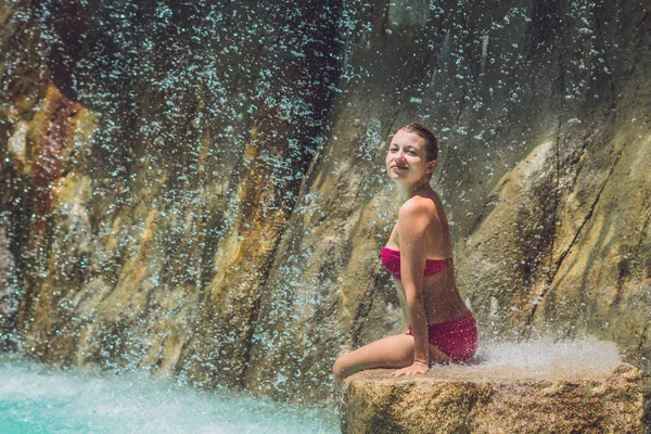 Junge Frau entspannt sich unter einem Wasserfall — Stockfoto