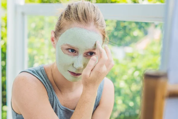 Mujer aplicando Facial máscara de arcilla verde — Foto de Stock