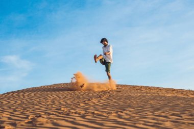 adam kırmızı bir çölde kum tekme atıyor