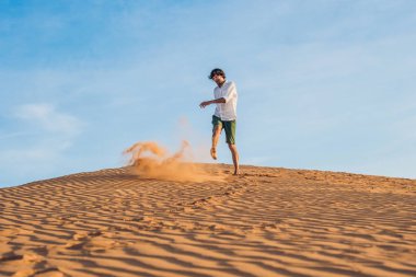 adam kırmızı bir çölde kum tekme atıyor