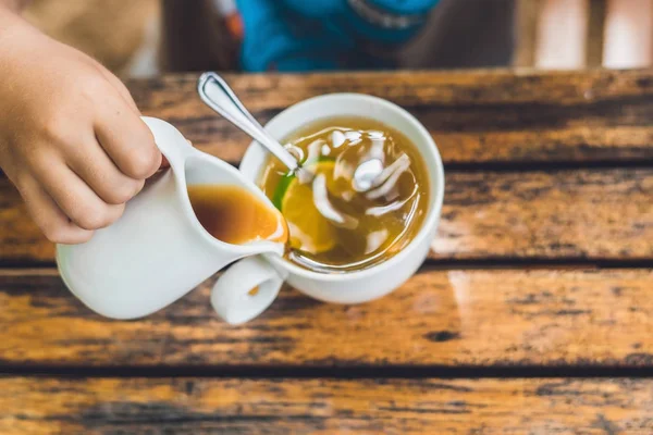 Anak menuangkan madu ke dalam teh — Stok Foto