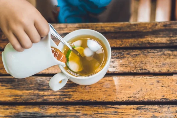 Anak menuangkan madu ke dalam teh — Stok Foto