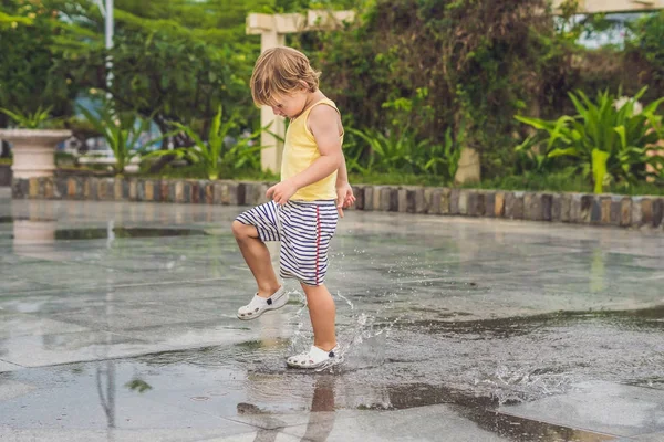 小さな男の子が水たまりを通る — ストック写真