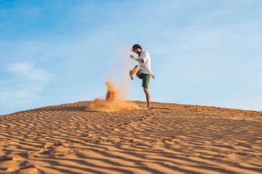 adam kırmızı bir çölde kum tekme atıyor