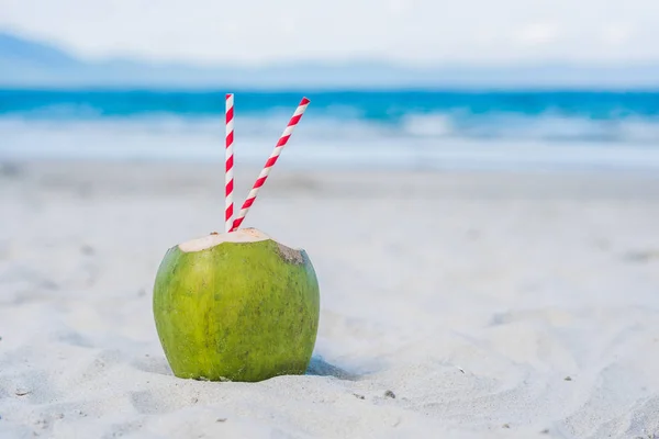 Kokosnuss mit Strohhalmen im Sand — Stockfoto