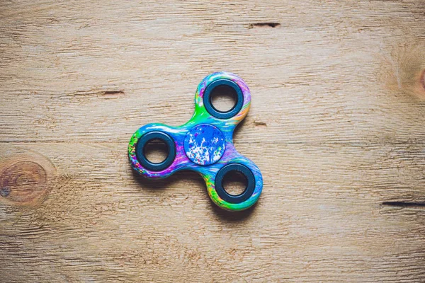 spotted fidget spinner stress relieving toy on wooden background.