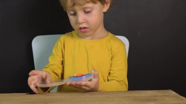 Bonito Filho Amarelo Camisa Caixa Aberta Com Spinner Brinquedo — Vídeo de Stock