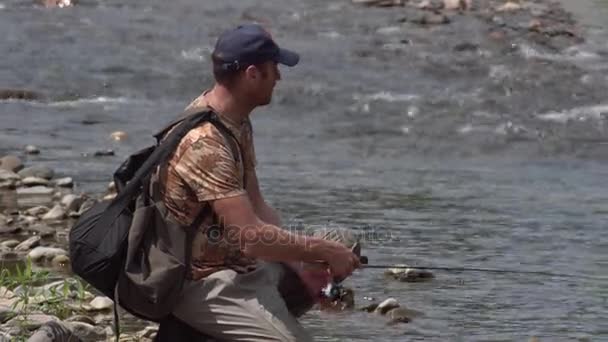 Hombre pescando en un río de montaña con una ultraligera girando usando wobblers de pesca — Vídeo de stock