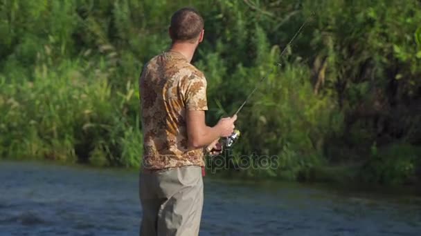 L'uomo pesca su un fiume di montagna con una filatura ultraleggera utilizzando wobblers pesca — Video Stock