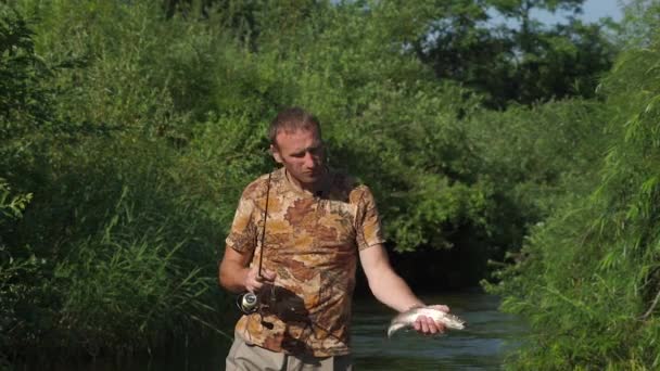 Fischer zeigt der Kamera einen Fisch, den er gerade mit einem kurzen ultraleichten Spinnrad gefangen hat — Stockvideo