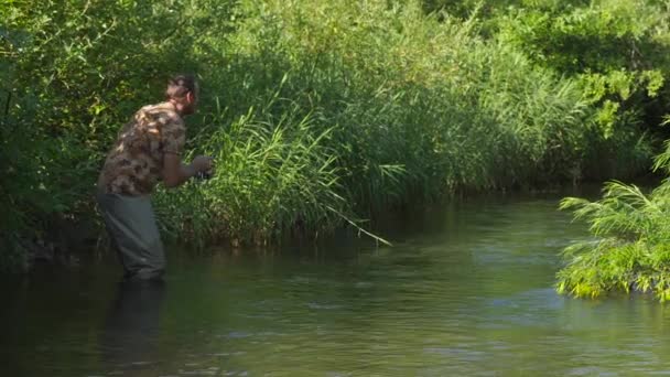 Homme pêchant sur une rivière de montagne avec un ultraléger filant à l'aide de wobblers de pêche — Video