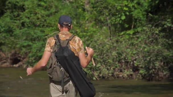 Hombre pescando en un río de montaña con una ultraligera girando usando wobblers de pesca — Vídeos de Stock