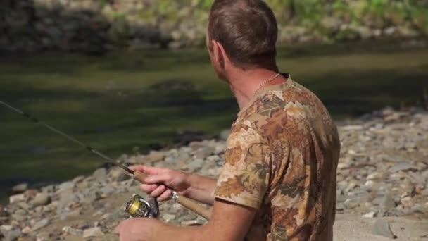 Gros plan d'un homme pêchant sur une rivière de montagne avec un ultra-léger filant à l'aide de wobblers de pêche — Video